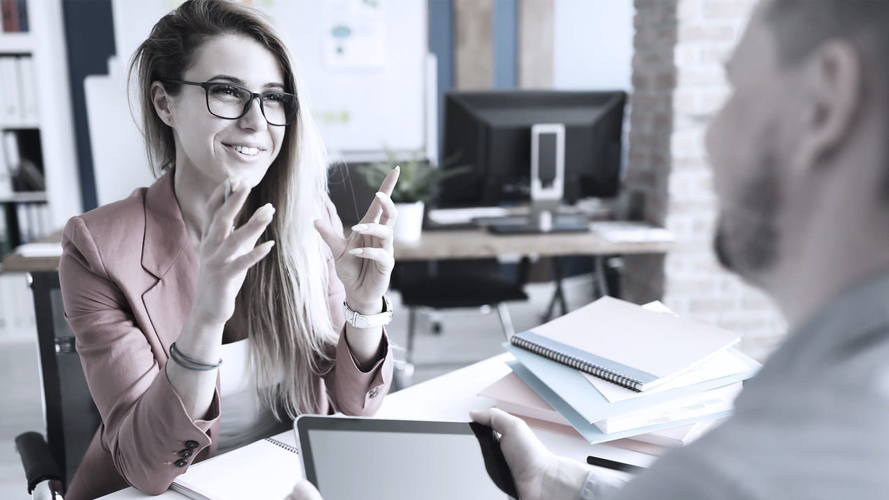 A woman is talking to a man in an office.