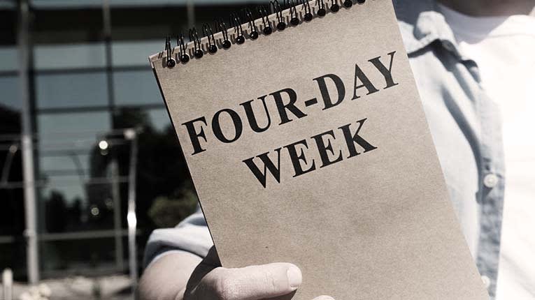 A man holding a notebook that says four - day week.