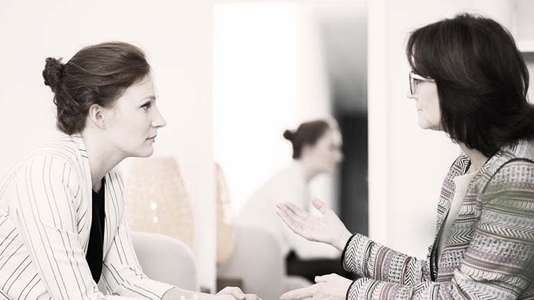 Two women talking to each other in an office.