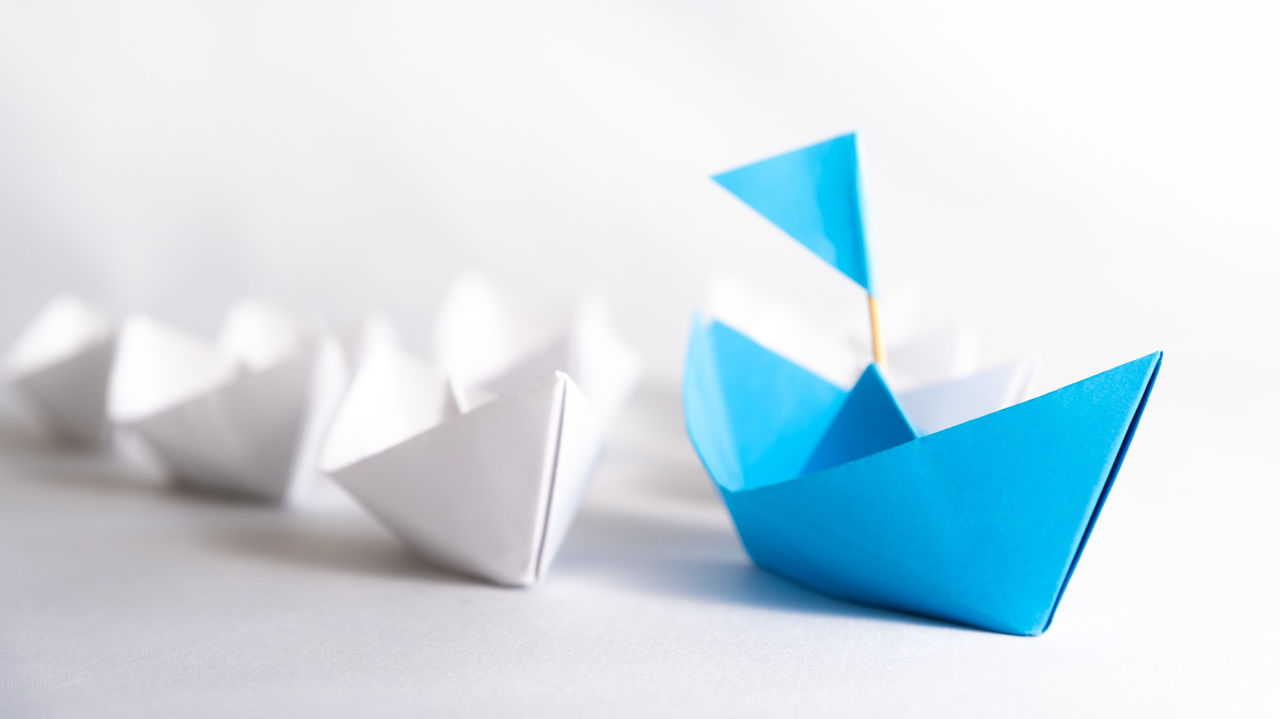 A group of blue and white origami boats on a white background.