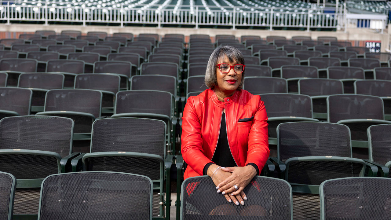 A woman in a red jacket sitting in an empty stadium.