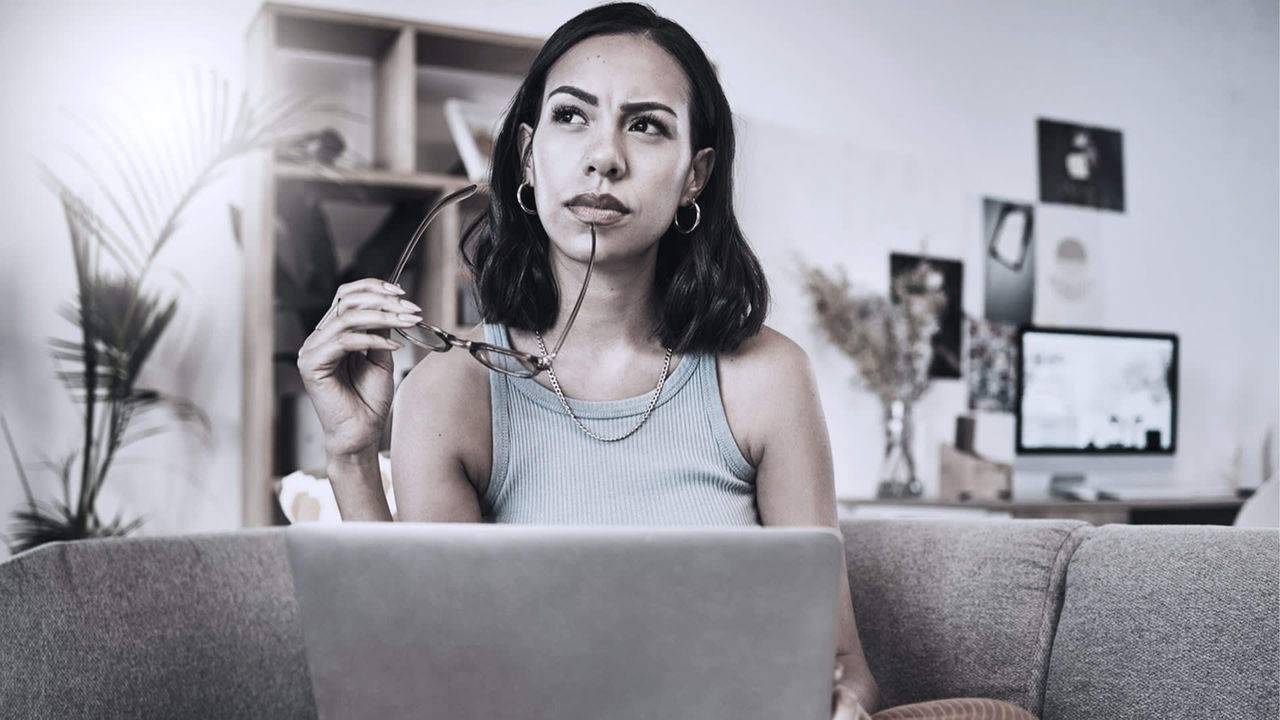 A woman is sitting on a couch and using a laptop.