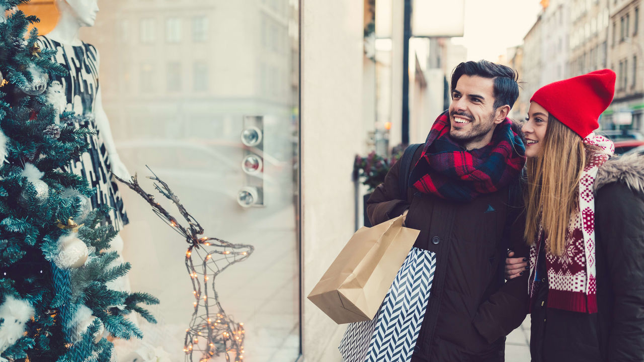 A couple looking at christmas decorations in a shop window.