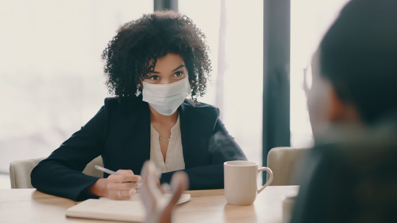 A woman wearing a face mask at a table.