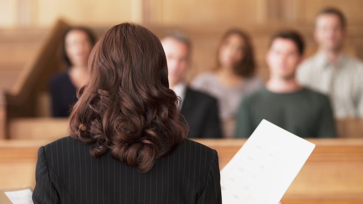 A woman in a suit standing in front of a courtroom.