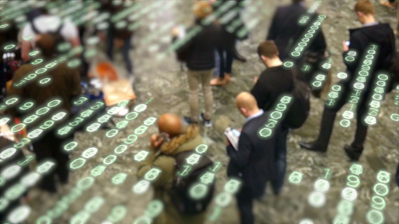 A group of people are standing in front of a computer screen.