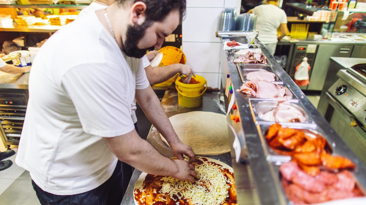 A man preparing a pizza in a restaurant.