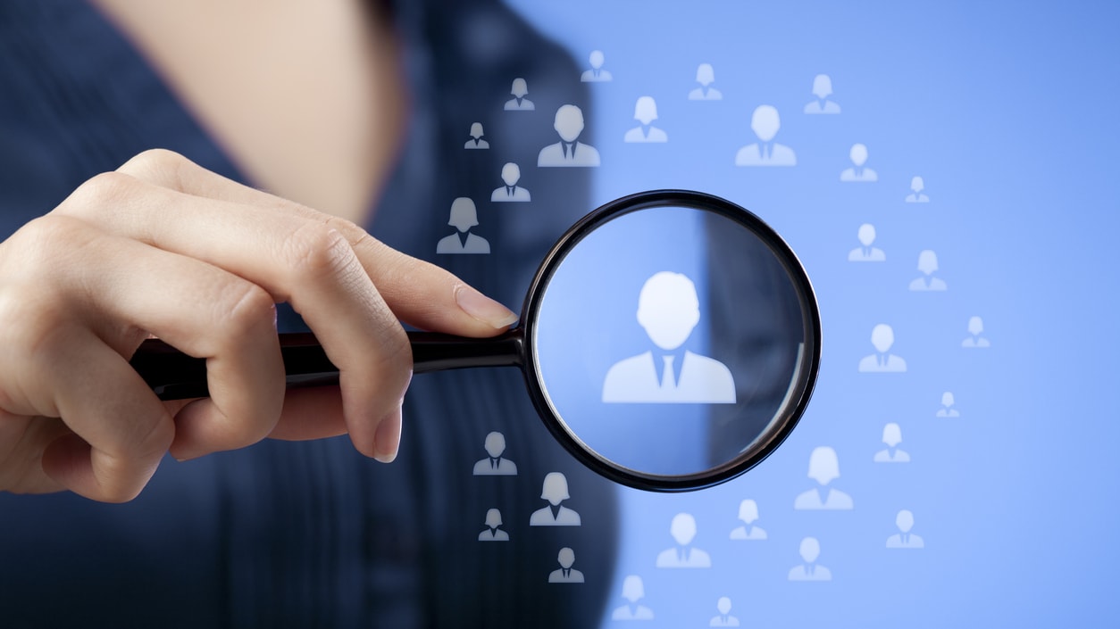 A professional holding a magnifying glass over a graphic of a person.