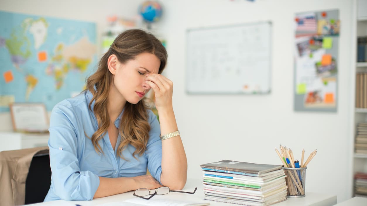 A woman is sitting at a desk with a book in front of her.