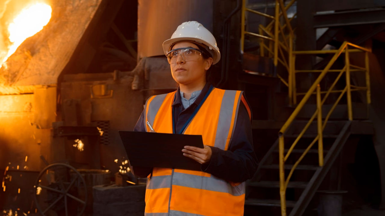 A worker at a steel factory holding a clipboard.