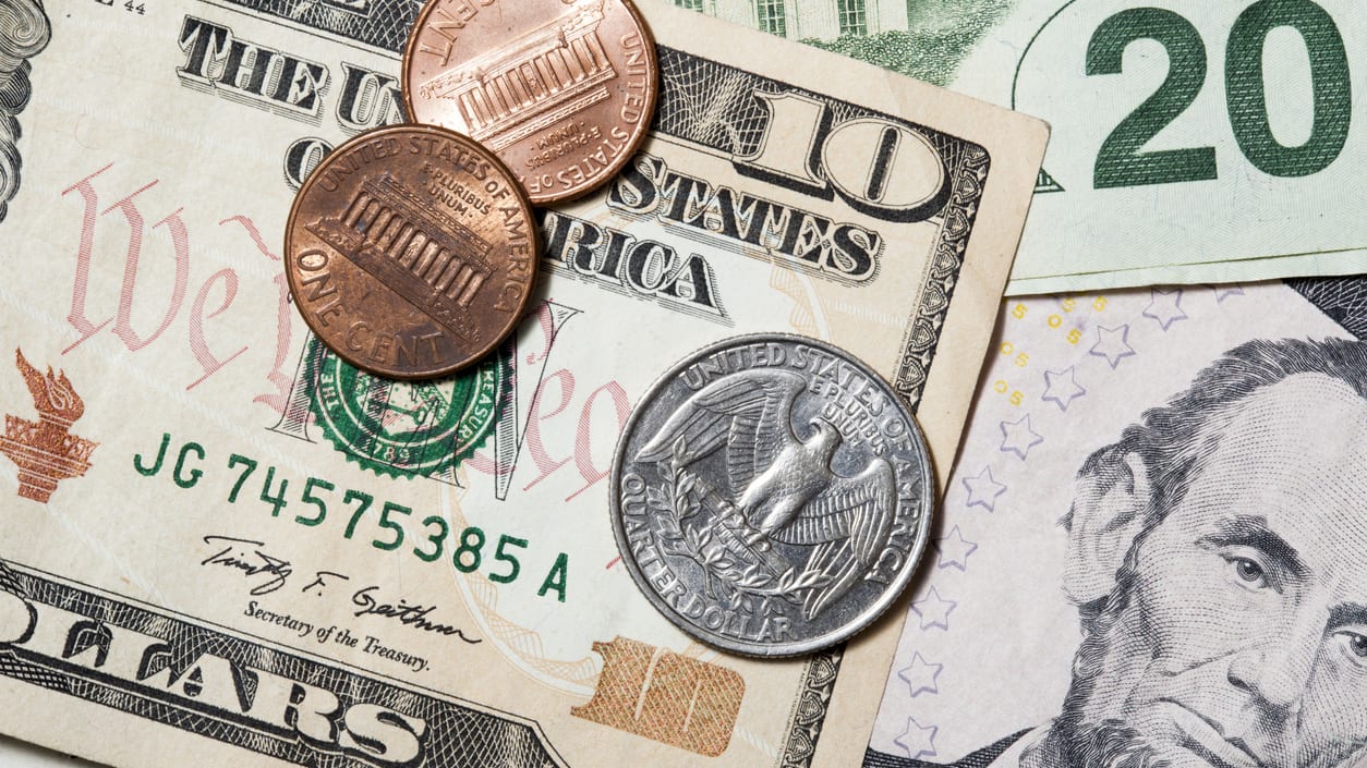 A stack of dollar bills and coins on a white background.