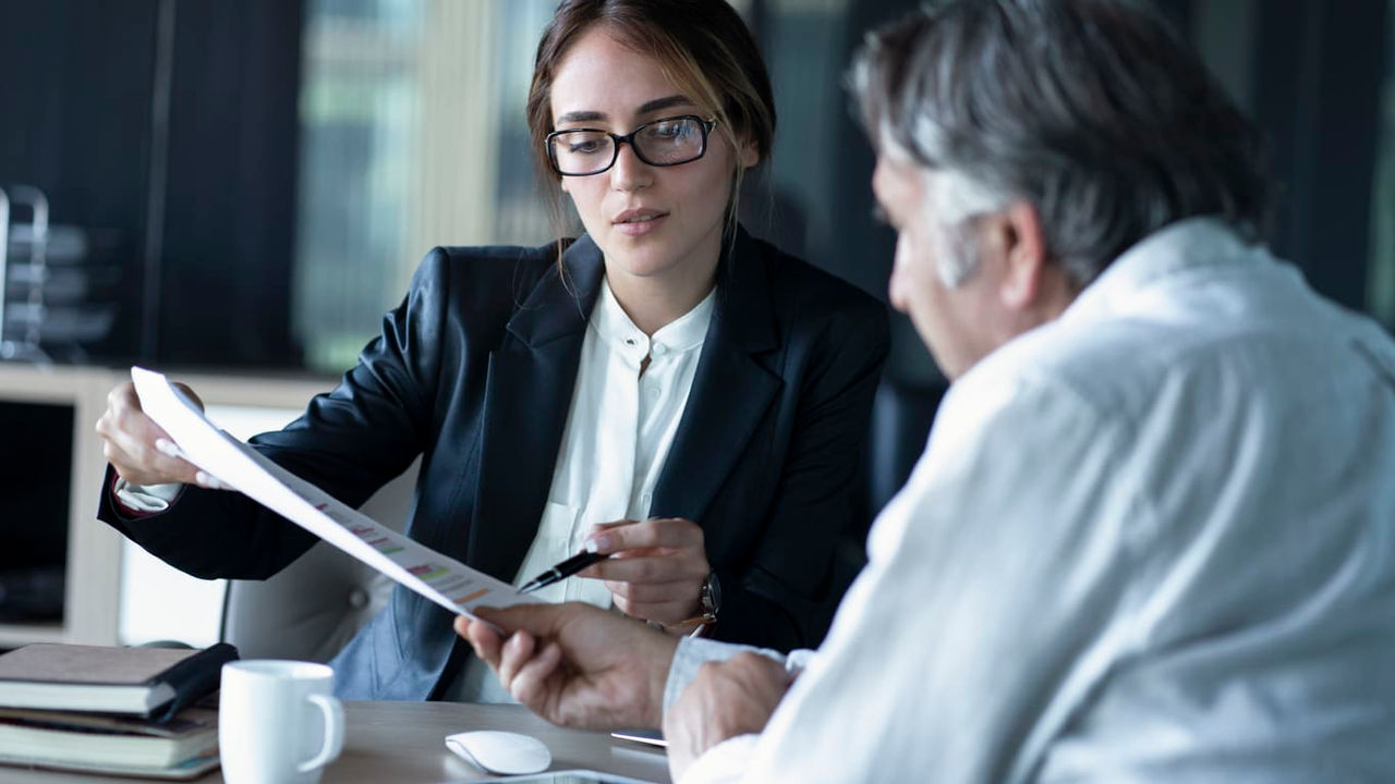 Two business people sitting at a table and talking to each other.