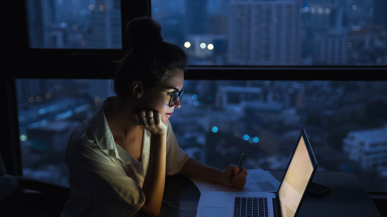 A woman working on her laptop at night.