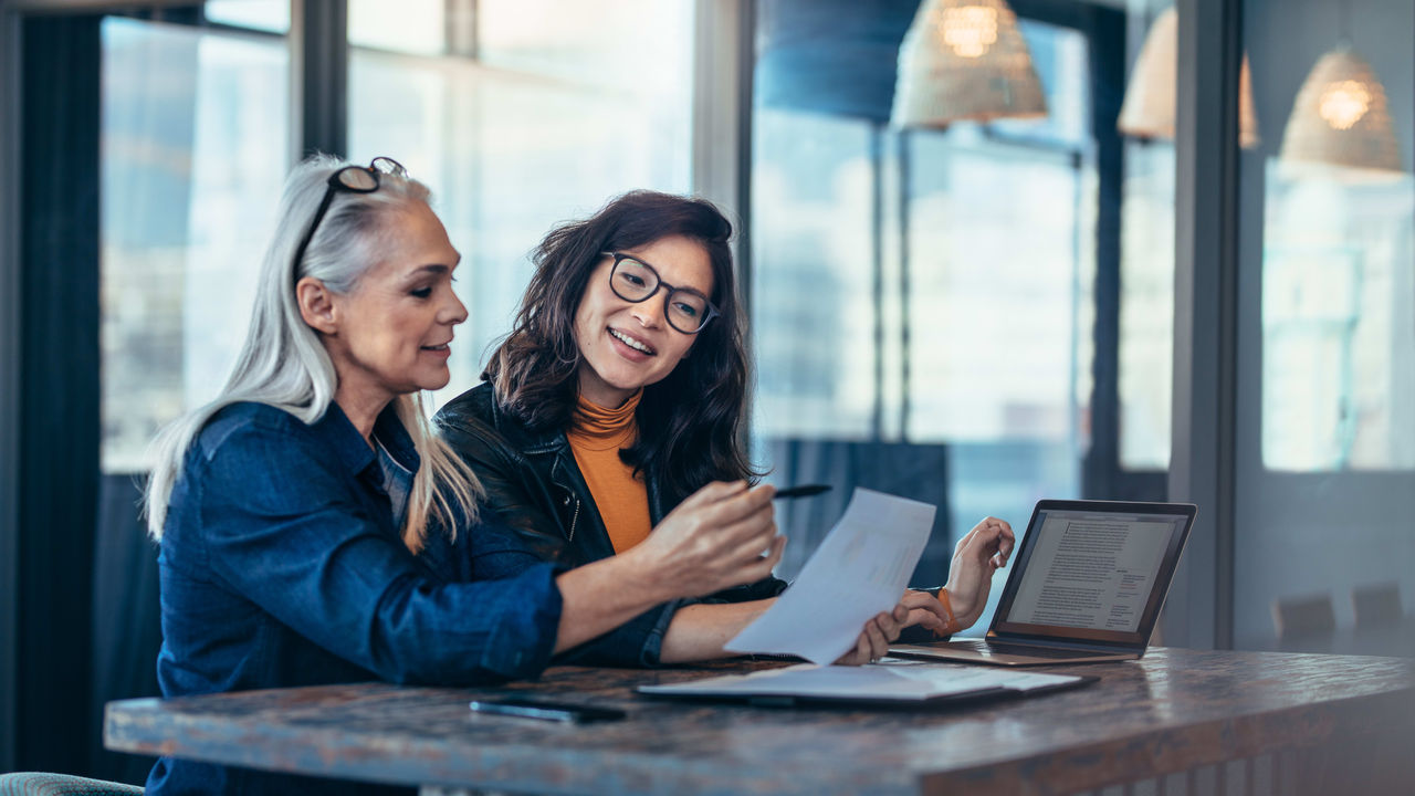 Two women working at a desk in an office.