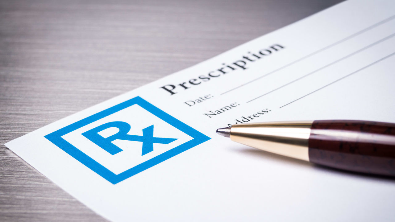 A prescription form with a pen on it.
