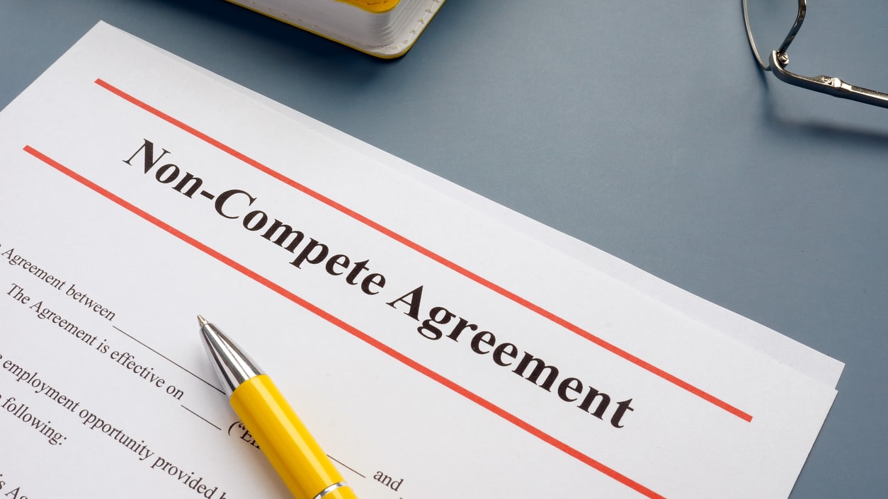 A non-compete agreement with a yellow pen on top.