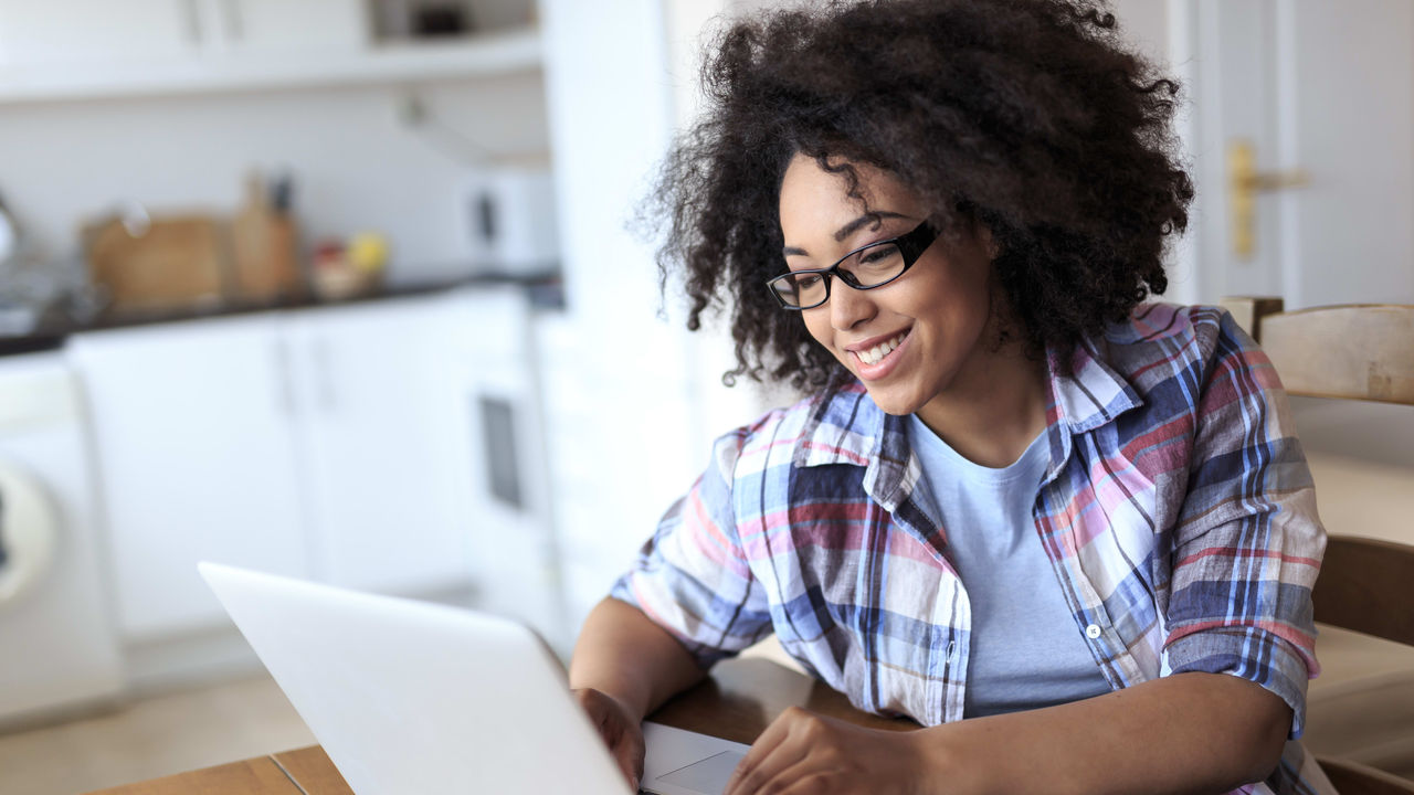 A young woman using a laptop in her kitchen.