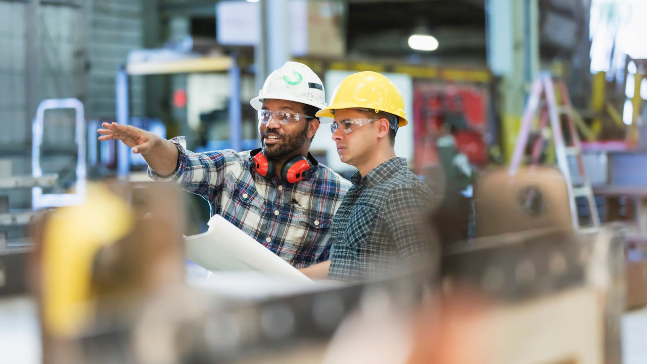 Two men in hard hats working in a factory.