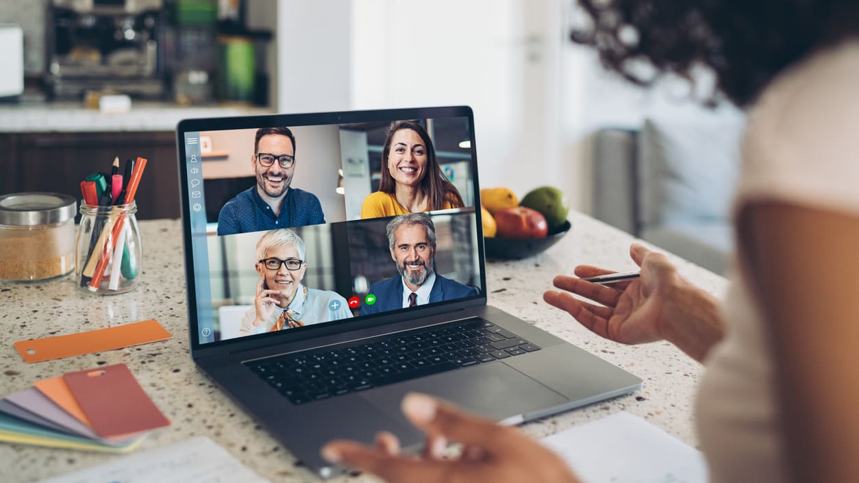 A woman is using a laptop with several people on it.