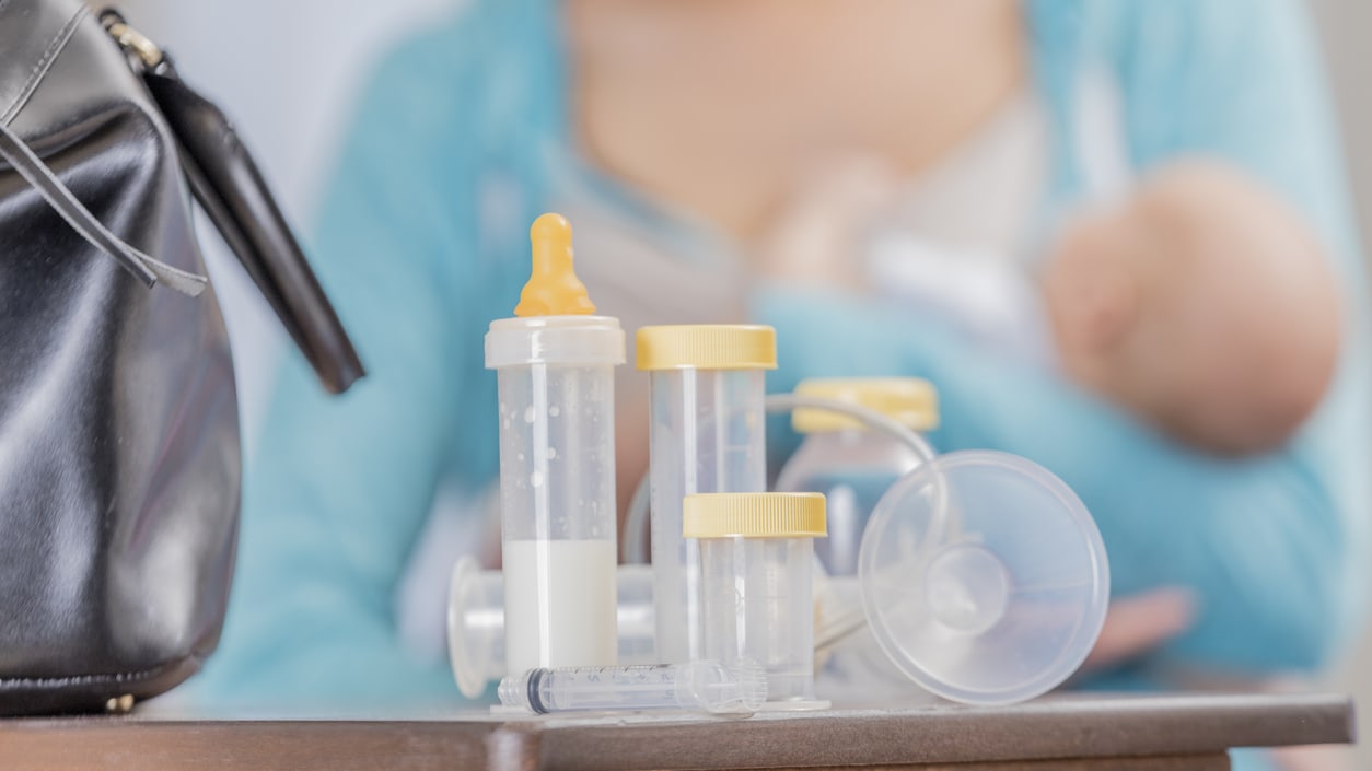 A woman with a baby in front of a bag.