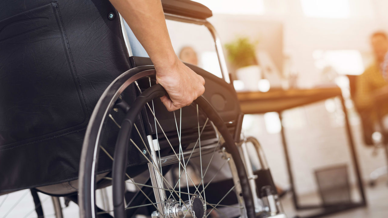 A man is sitting in a wheelchair in front of a group of people.