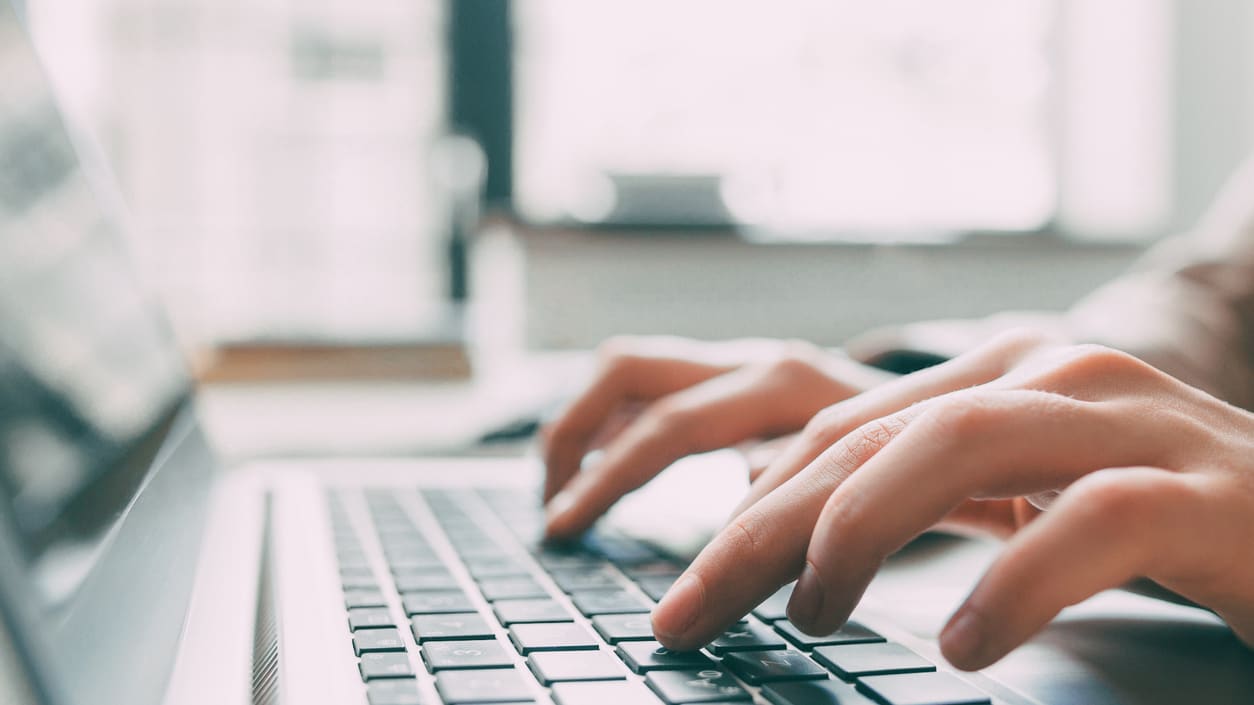 A person typing on a laptop keyboard.