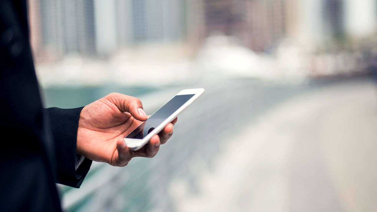 A man in a suit is holding a smart phone.