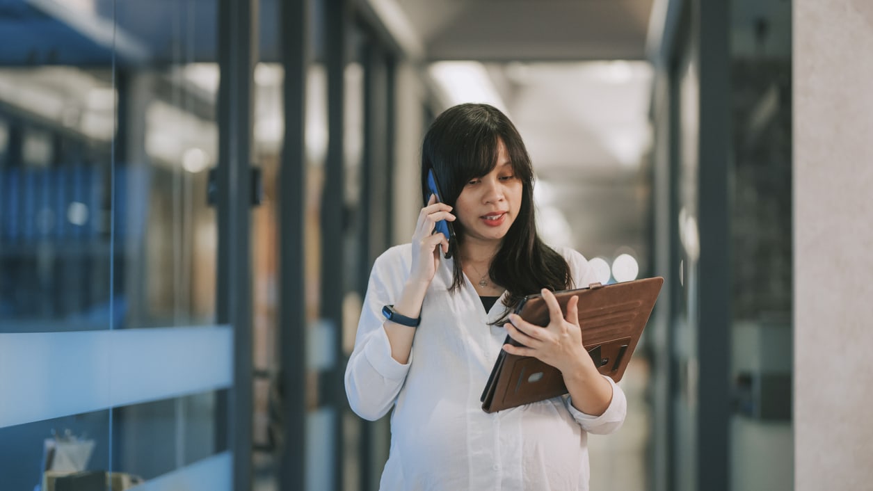 Asian female doctor talking on the phone while standing in an office.