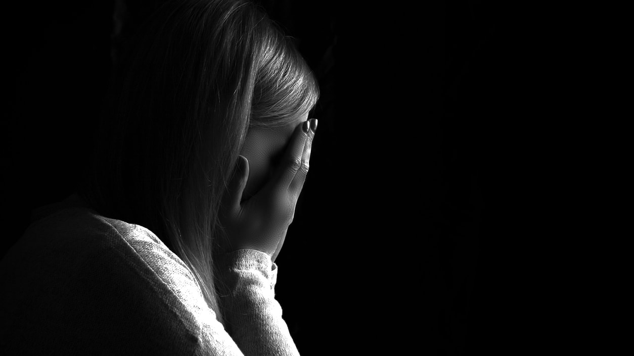 A black and white photo of a woman covering her face.
