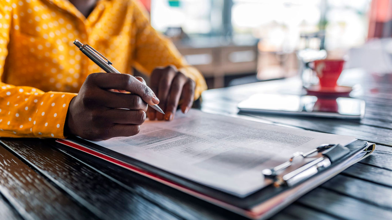 A woman is signing a document at a table.