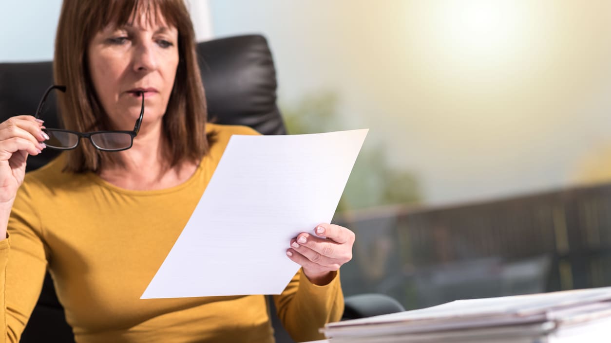 A woman looking at a piece of paper at an office desk.
