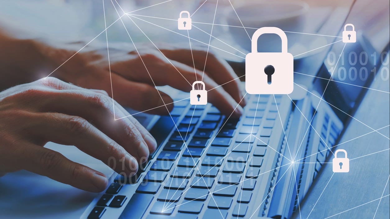 A person typing on a laptop with a padlock on it.