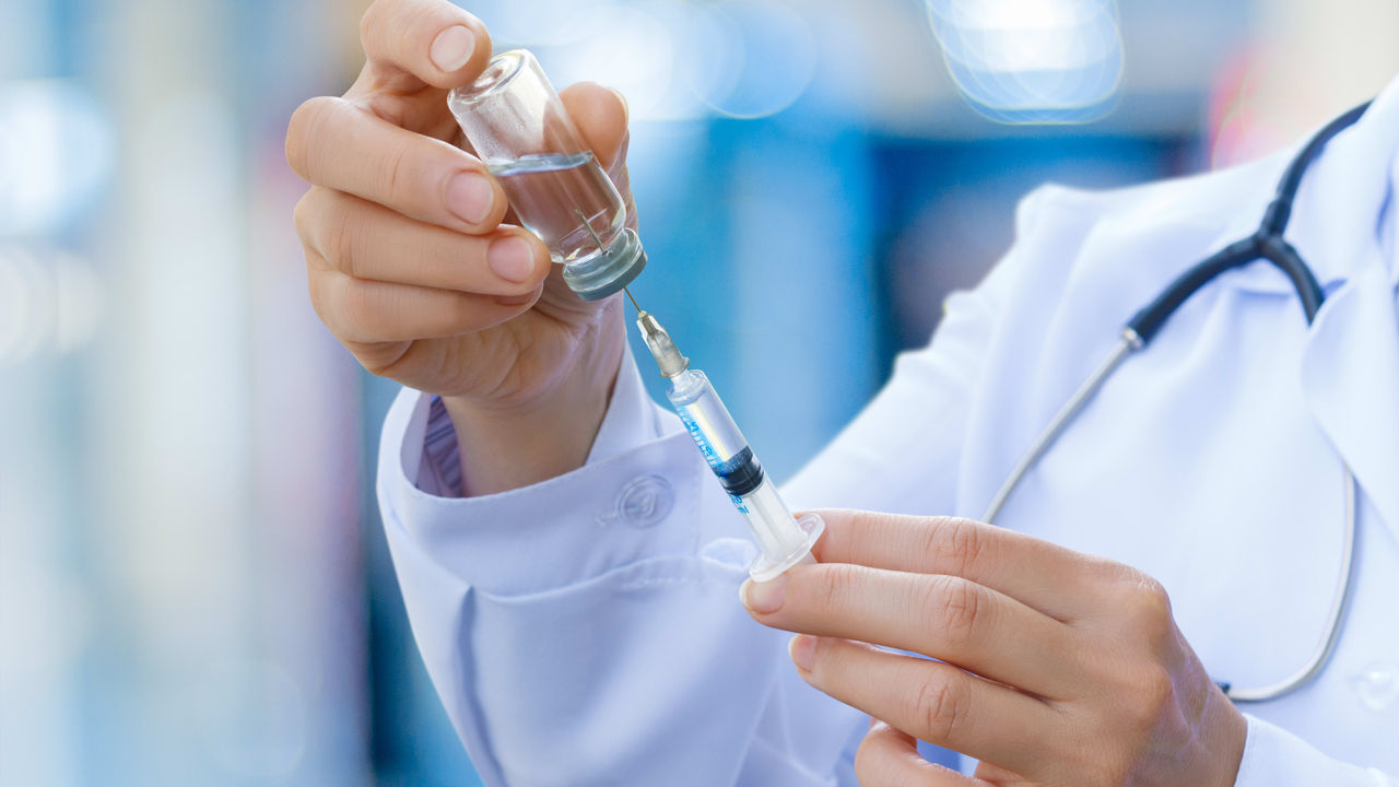 A doctor is holding a syringe in his hand.