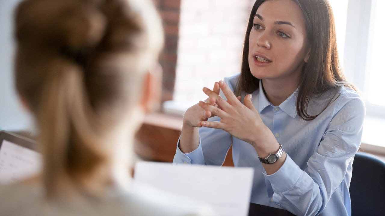 A woman is talking to another woman in an office.