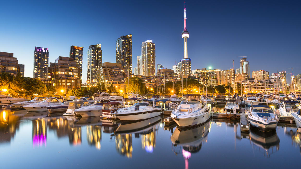 Toronto skyline at dusk with boats docked in the harbor.
