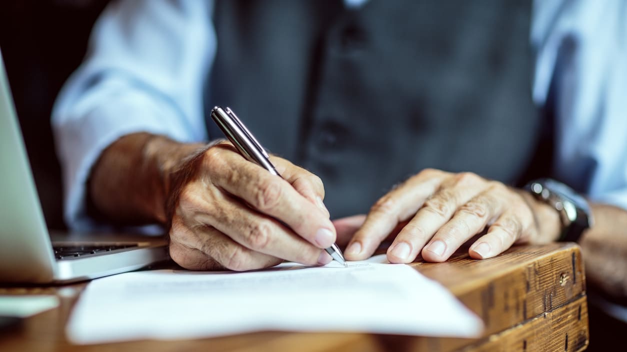 A man signing a document with a pen.