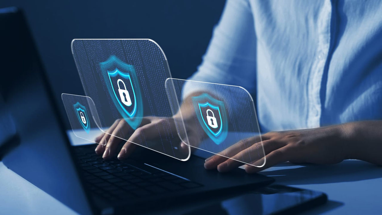 A woman is using a laptop with a security symbol on it.