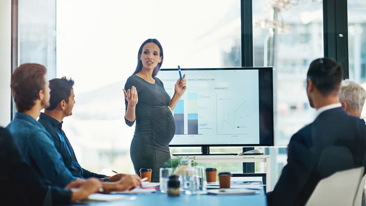 A business woman giving a presentation to a group of people.