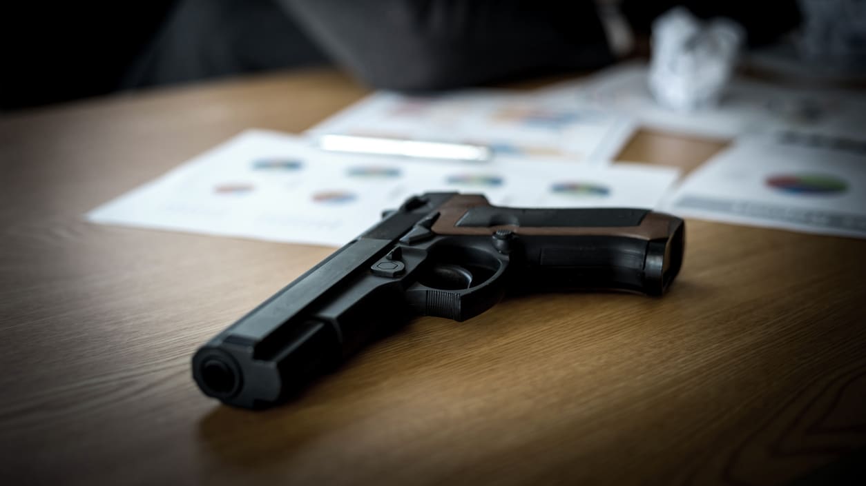 A gun is sitting on a table in front of a person.