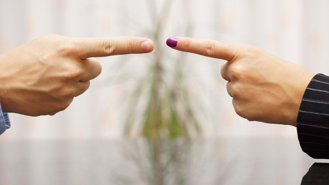 Two business people pointing their fingers at each other.