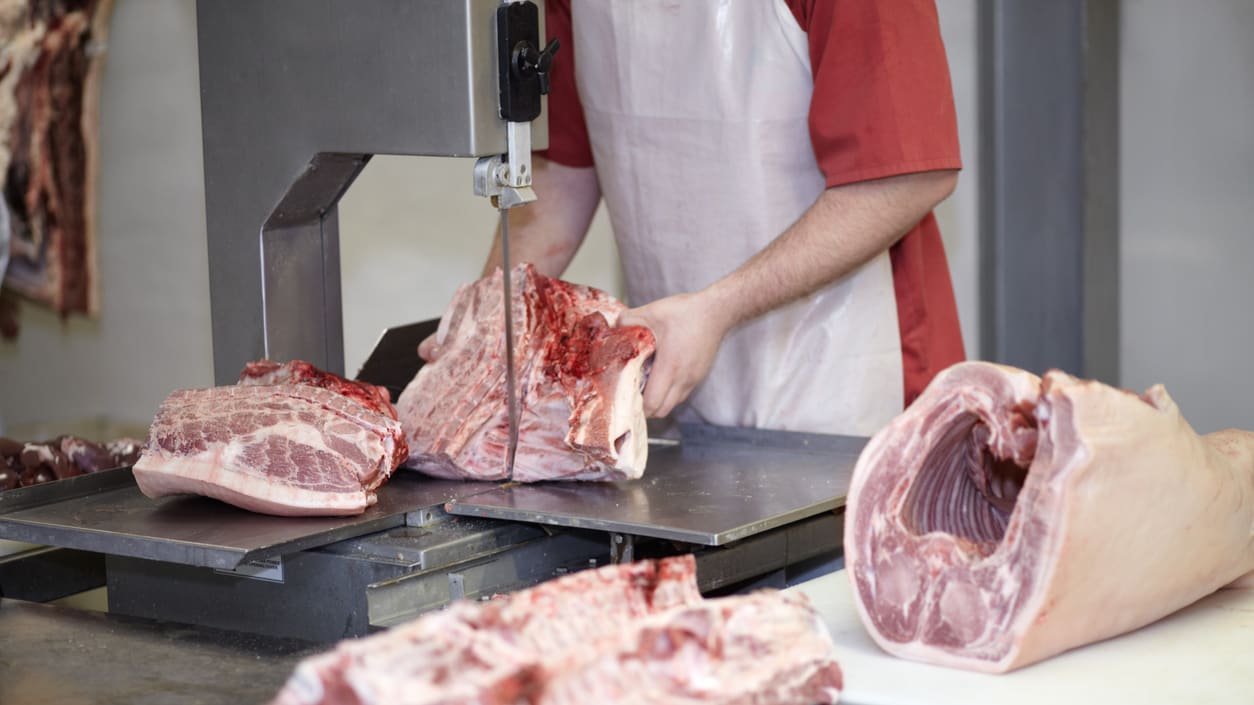 A man is slicing meat on a cutting board.