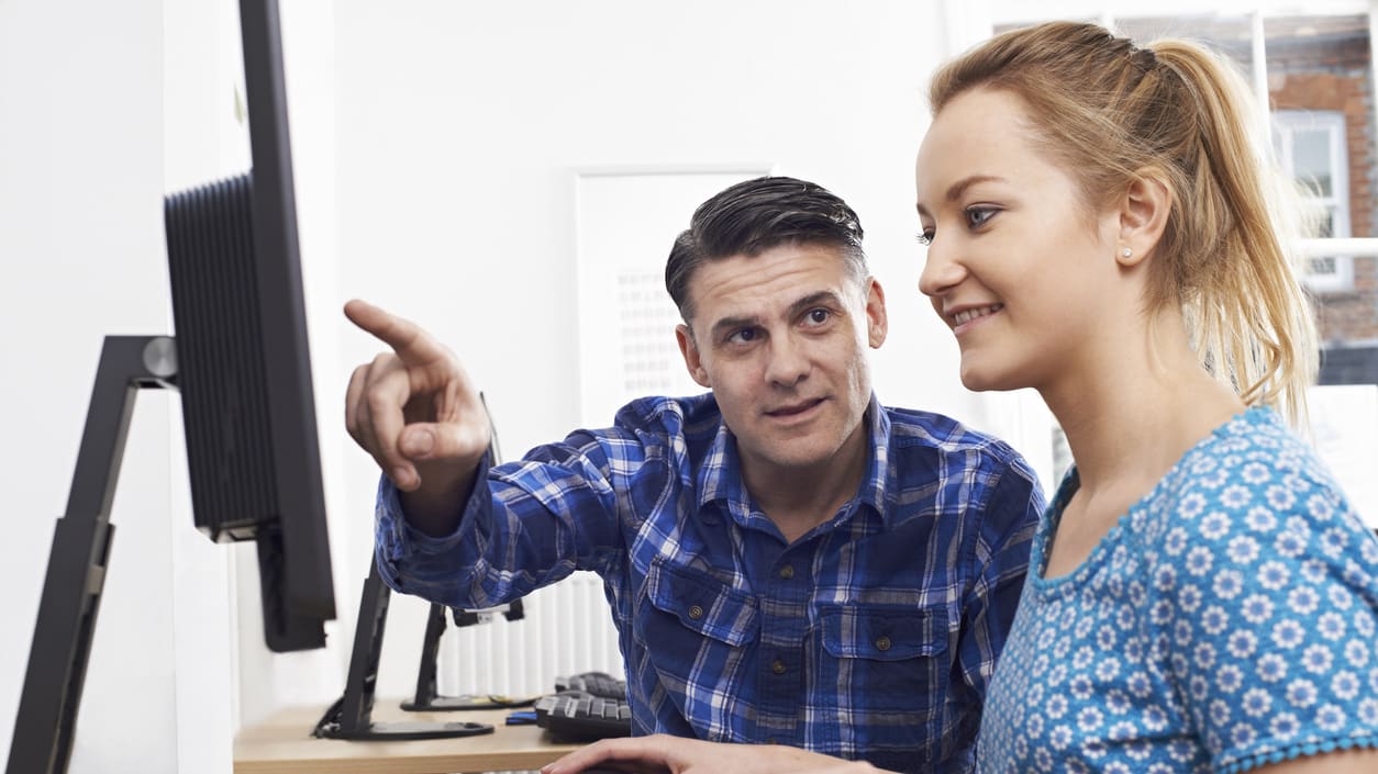 A man and a woman sitting in front of a computer.