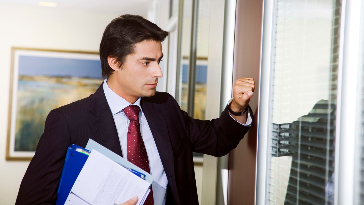 A businessman holding a folder in front of a window.