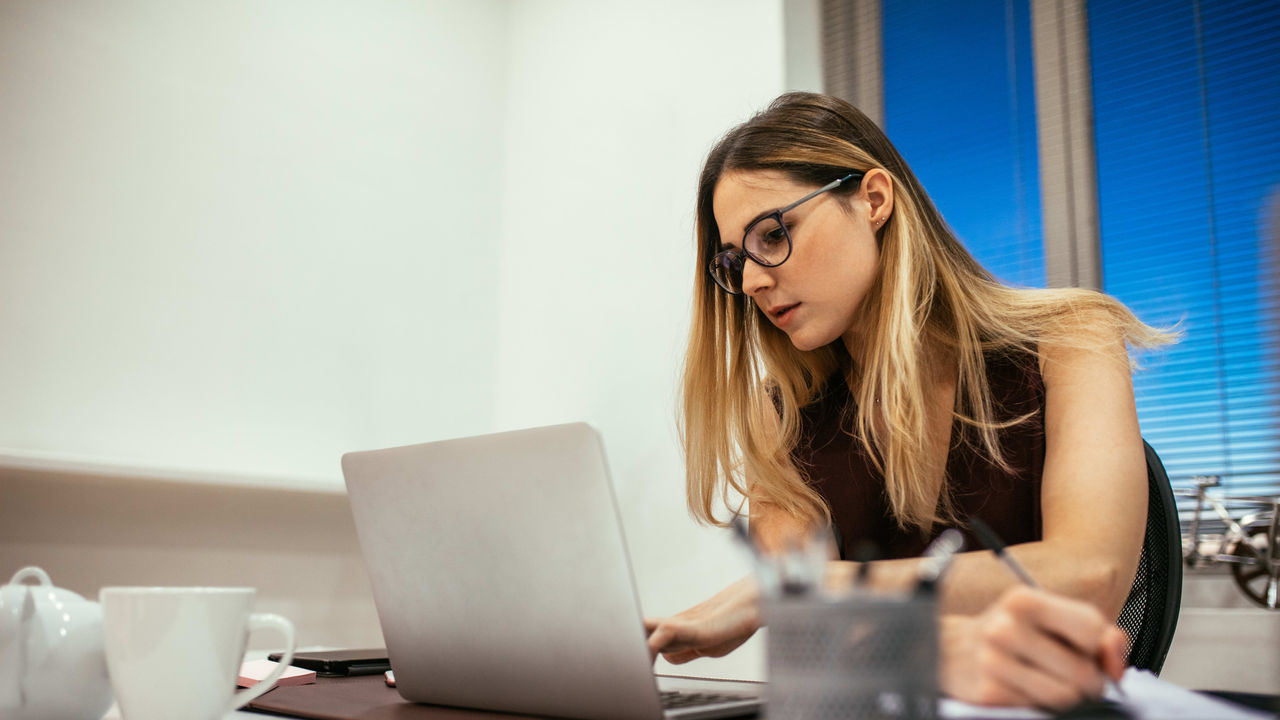 A woman working on a laptop in an office.