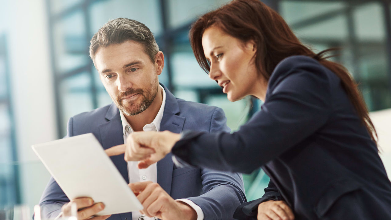 Two business people looking at a tablet in an office.