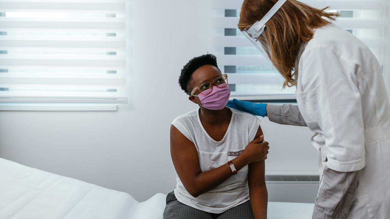 A woman wearing a face mask is talking to a patient in a hospital.