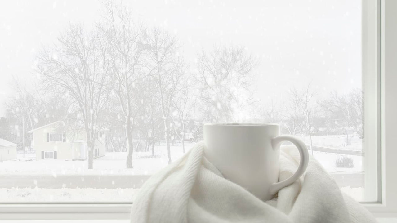 A cup of coffee sits on a window sill.