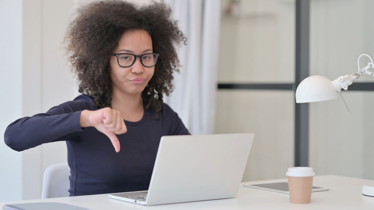 A woman is sitting at a desk with a laptop in front of her.