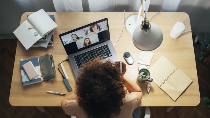 A woman sitting at a desk with a laptop and a cup of coffee.