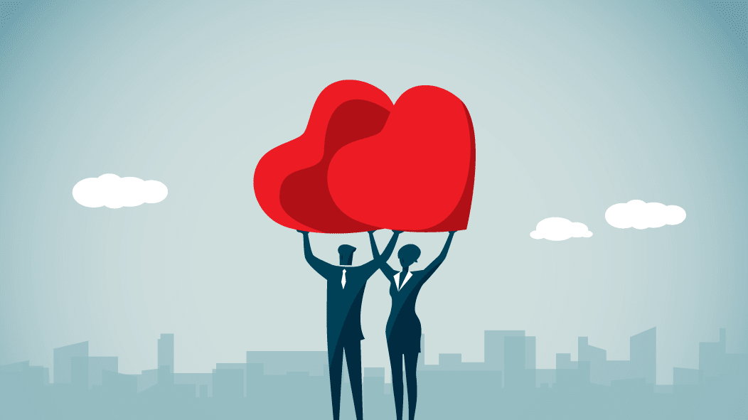 Two business people holding up a red heart in front of a city.